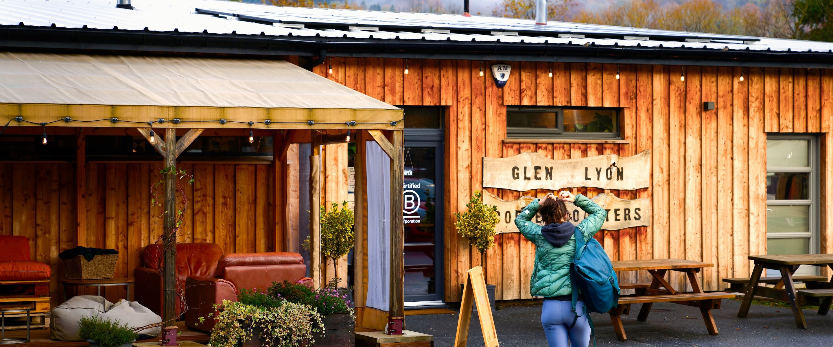 A banner exterior shot of a customer carrying a bag walking towards the Glen Lyon Coffee roastery cafe on a rainy day