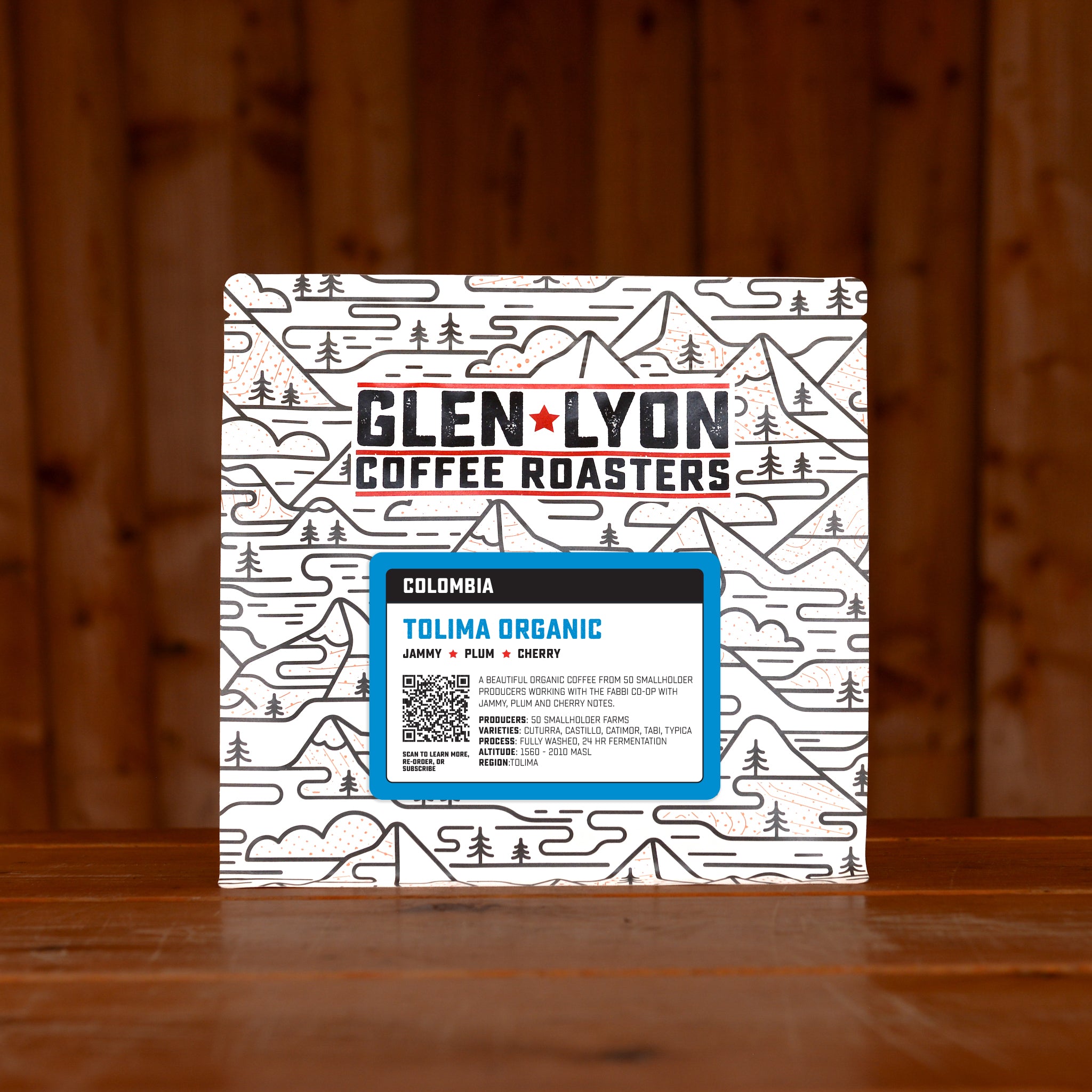 Blue Colombia Tolima Organic  information sticker on a Glen Lyon branded coffee bag, sitting on a wooden table with a wood panel background.