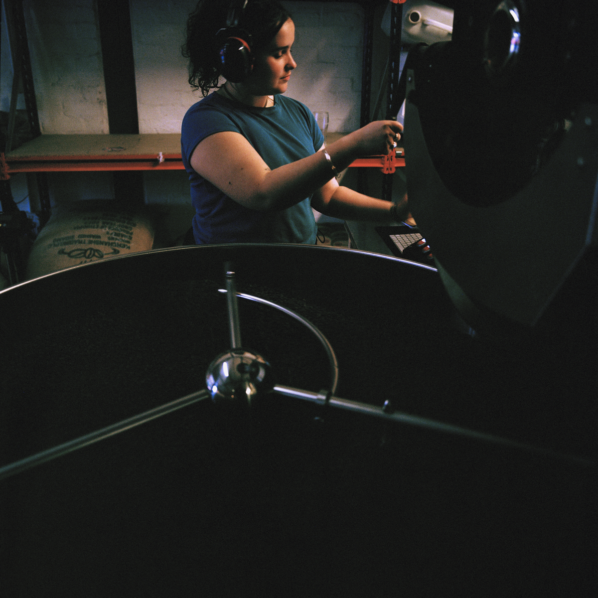 Moody medium shot of a staff member roasting coffee at the Glen Lyon Coffee roastery