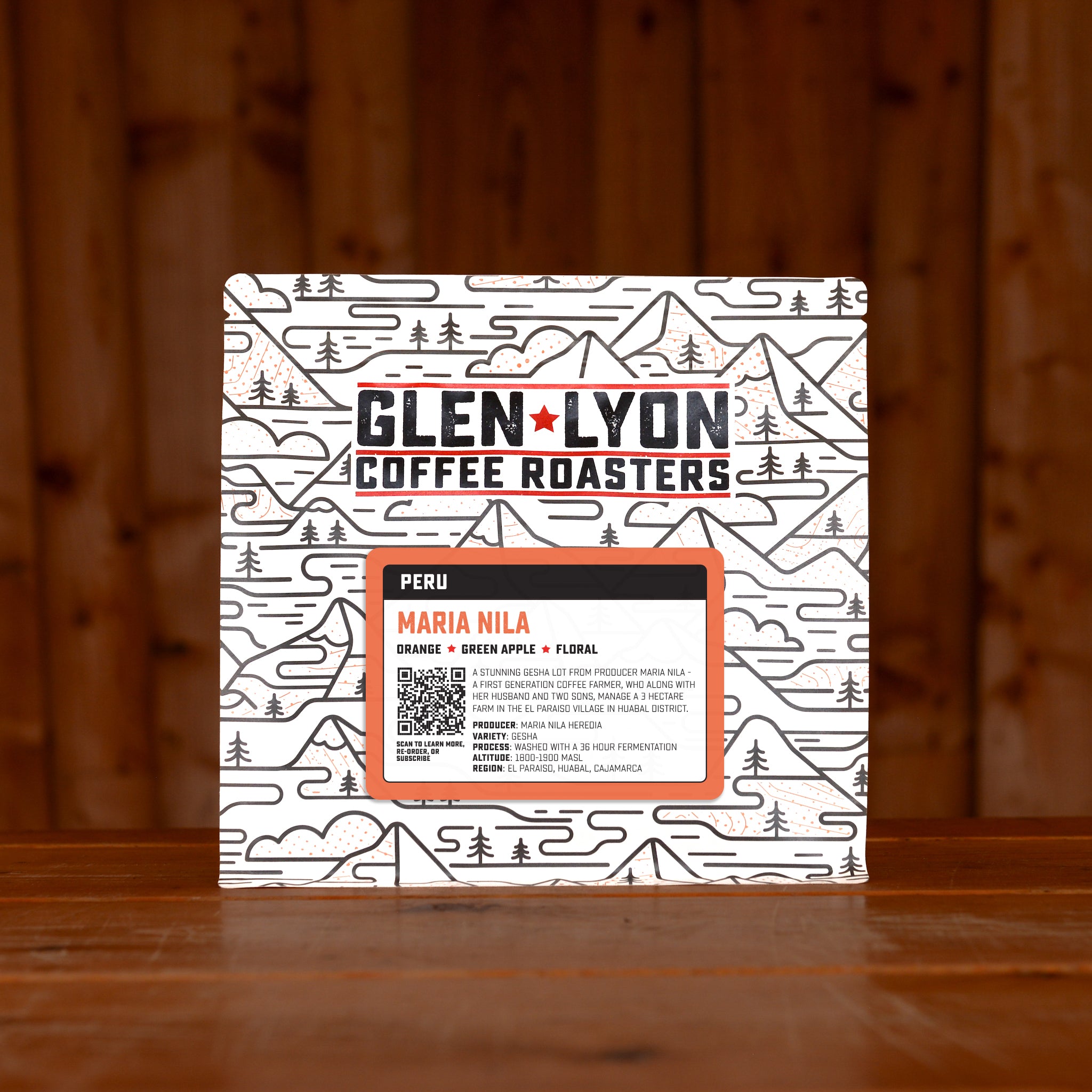 Peach-coloured Peru Maria Nila  information sticker on a Glen Lyon branded coffee bag, sitting on a wooden table with a wood panel background.