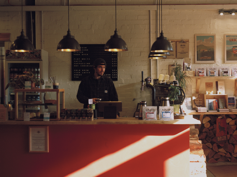 Mobile version of a wide interior shot of Glen Lyon Coffee Roasters' roastery cafe with a barista standing behind the bar