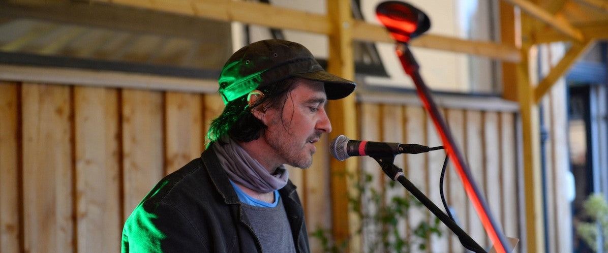 Medium shot of a person standing in front of a microphone outside the Glen Lyon Coffee roastery cafe