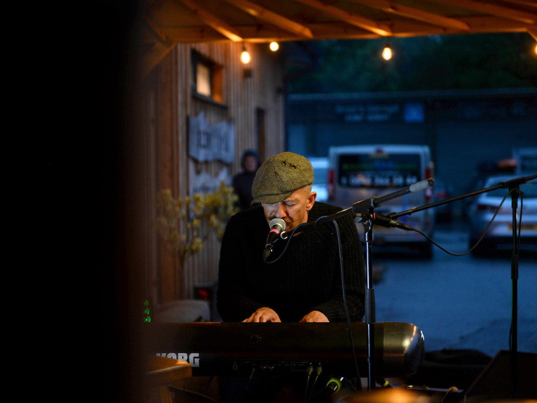 Mobile version of a musician playing the piano and singing outside the Glen Lyon Coffee roastery cafe