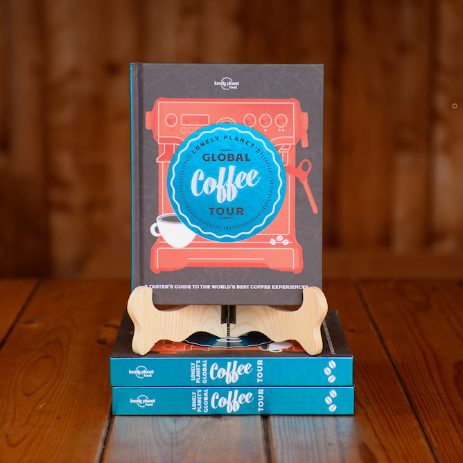The book Lonely Planet's Global Coffee Tour displayed on a book stand on a wooden table