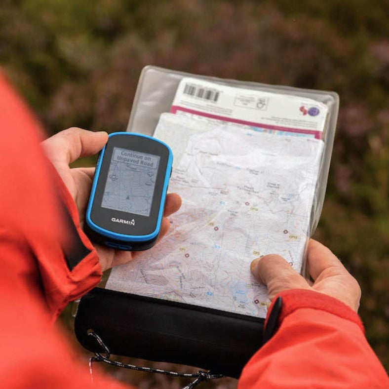 A close up of someone holding a map and digital compass