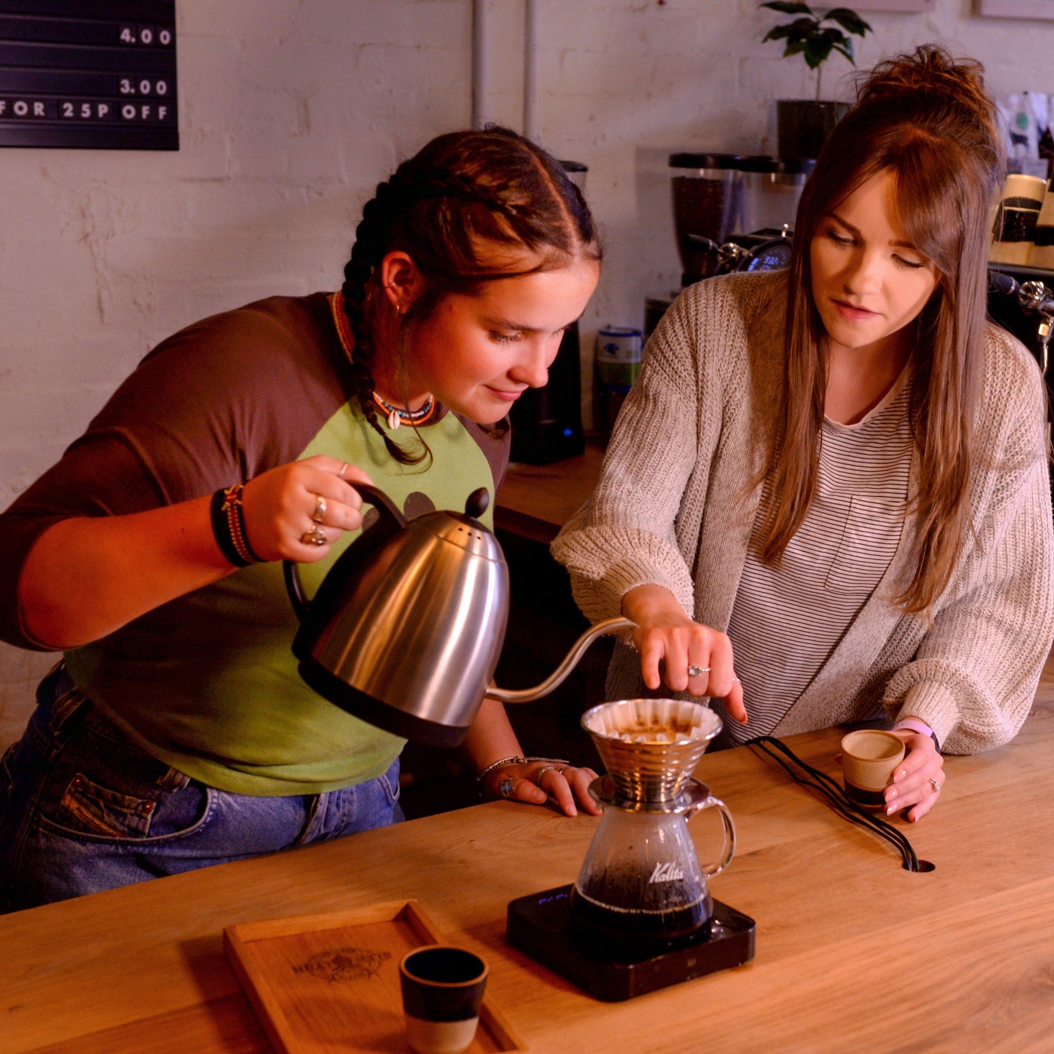 Two people stand behind the bar making a pour over at Glen Lyon Coffee Roasters roastery cafe