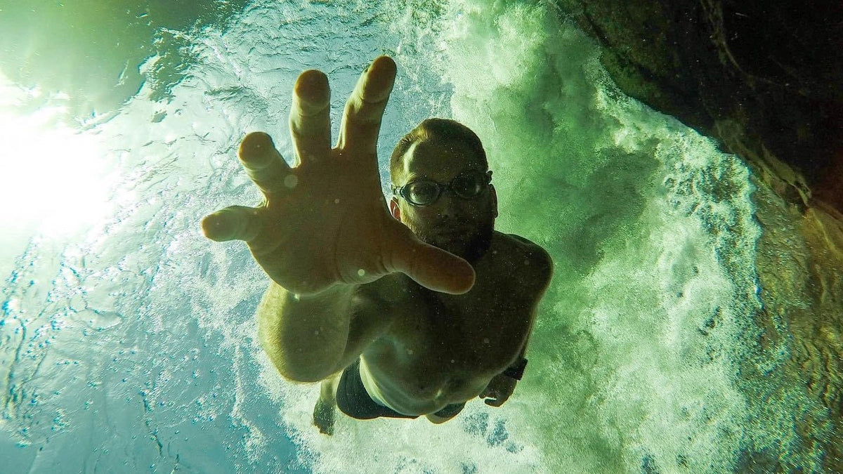 Calum Maclean dives down underwater reaching out for the camera