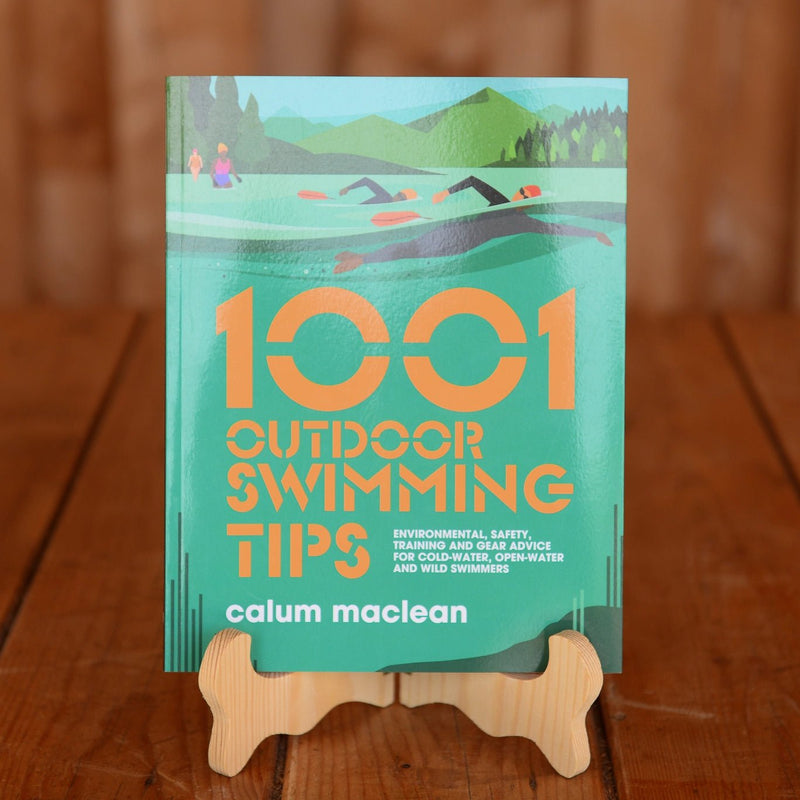 The book 1001 Outdoor Swimming Tips by Calum Maclean displayed on a book stand on a wooden table