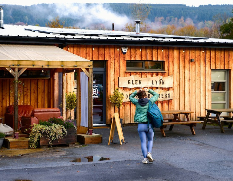 An exterior shot of a customer carrying a bag walking towards the Glen Lyon Coffee roastery cafe on a rainy day