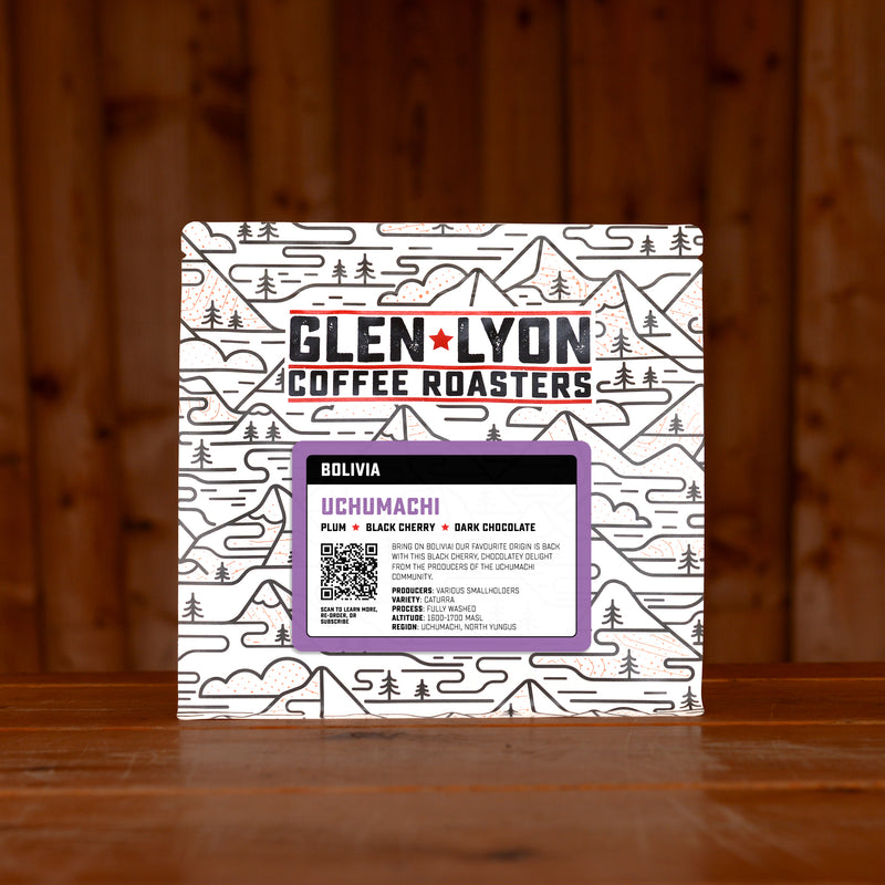 A 250g bag of Uchumachi from Glen Lyon Coffee Roasters coffee sits on a wooden table with a slatted wood background.