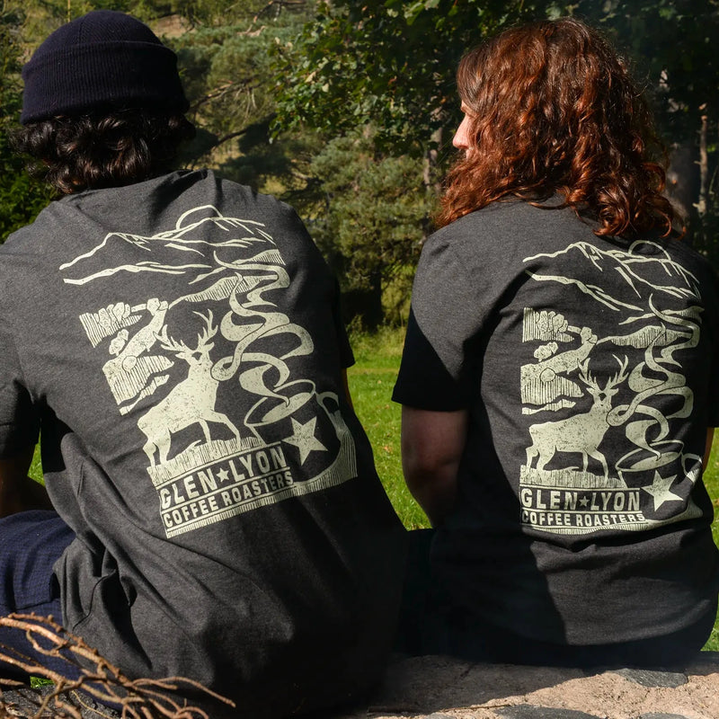 Brand ambassadors Anna Danby and Pretam Gurung rest wearing grey shirts with a white-ish coffee, stag, and mountain design.