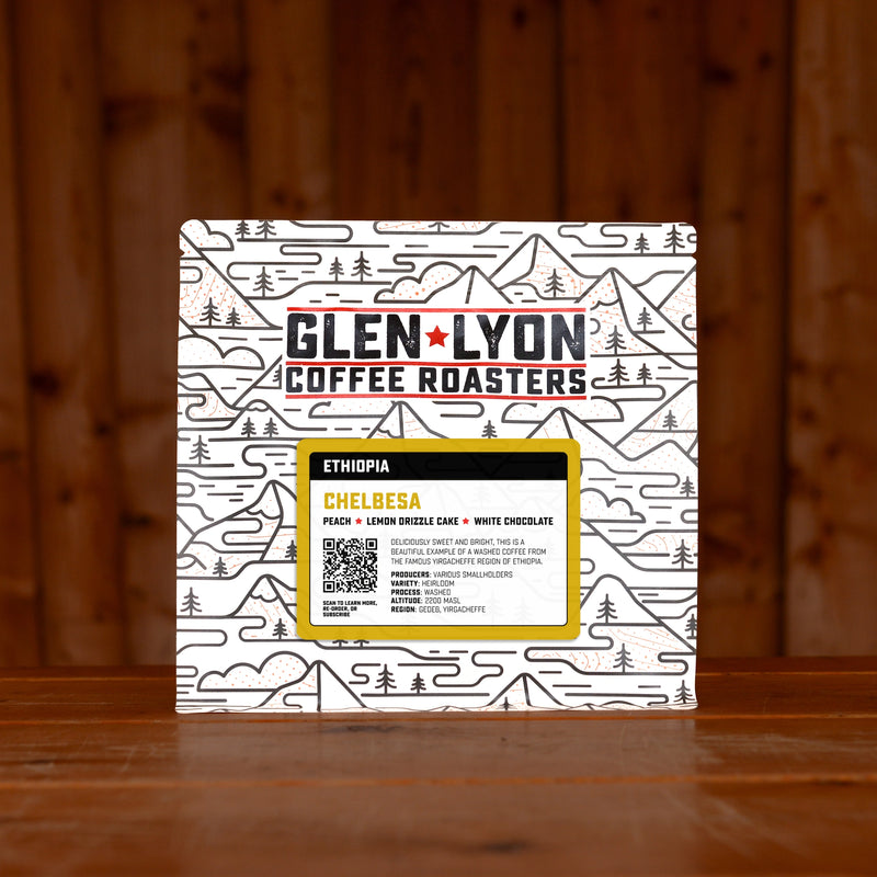 A 250g bag of Chelbesa from Glen Lyon Coffee Roasters coffee sits on a wooden table with a slatted wood background.