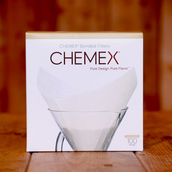 A box of Chemex filter papers on a wooden table