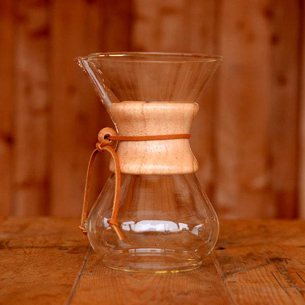 A glass Chemex speciality coffee brewer on a wooden table