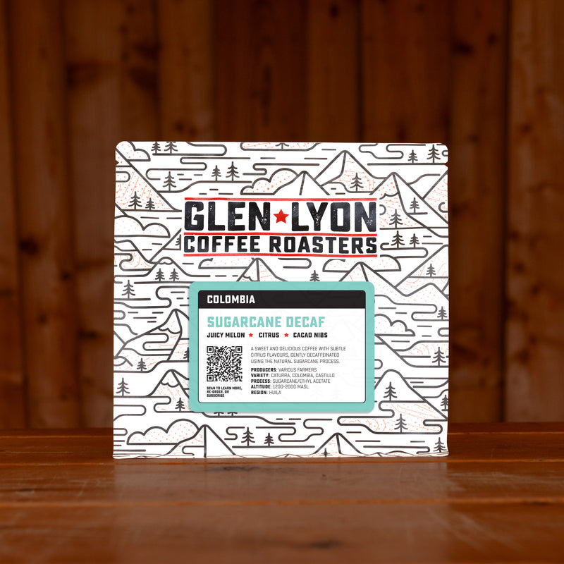 A 250g bag of Sugarcane Decaf from Glen Lyon Coffee Roasters coffee sits on a wooden table with a slatted wood background.