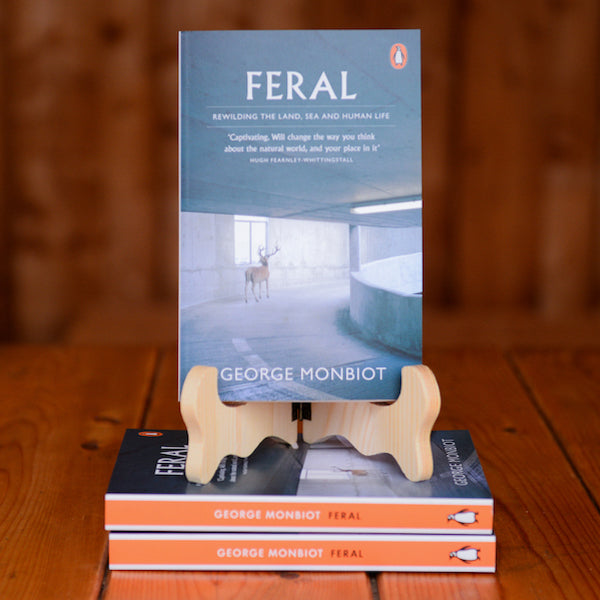 The book Feral by George Monbiot displayed on a book stand on a wooden table