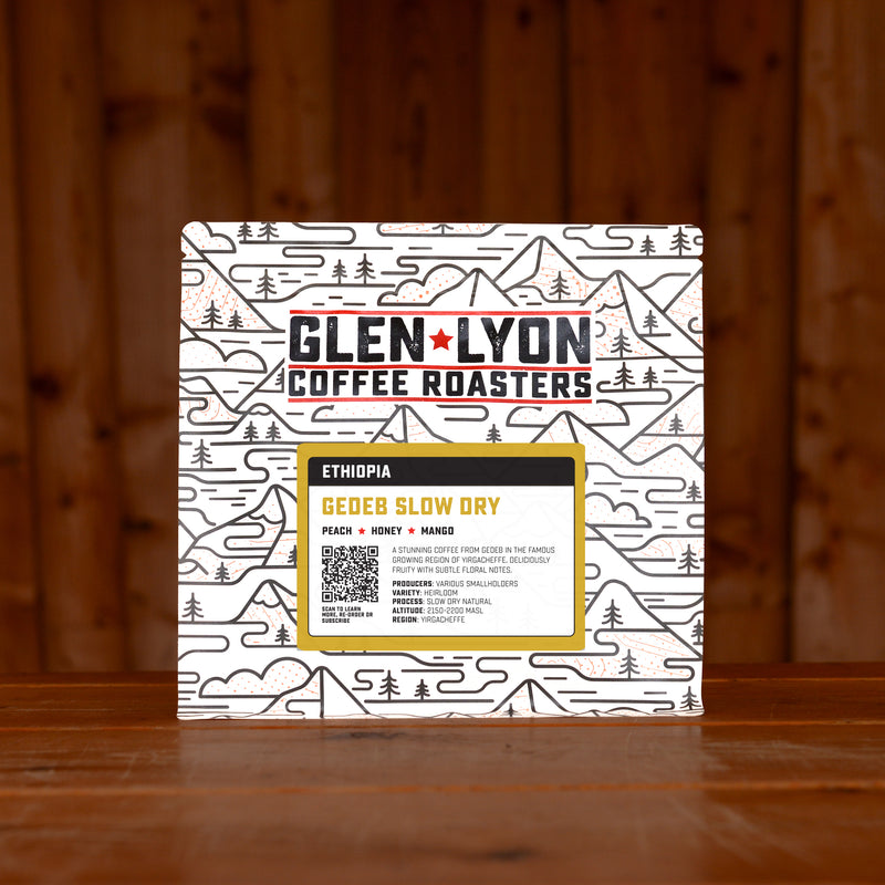 A 250g bag of Gedeb Slow Dry from Glen Lyon Coffee Roasters coffee sits on a wooden table with a slatted wood background.