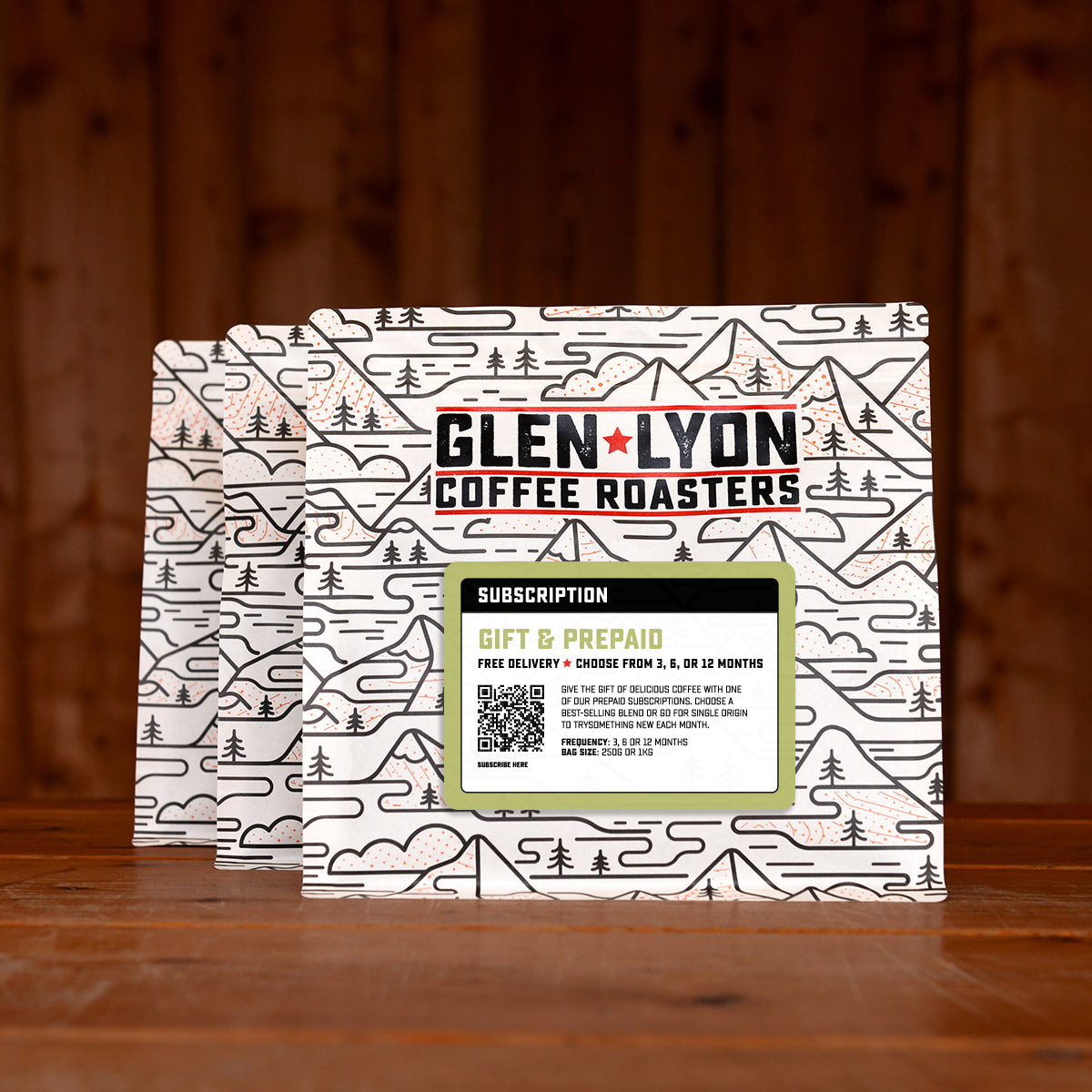 3 bags of gift and prepaid subscription labelled speciality coffee from Glen Lyon Coffee Roasters against a warm wood-tinged background