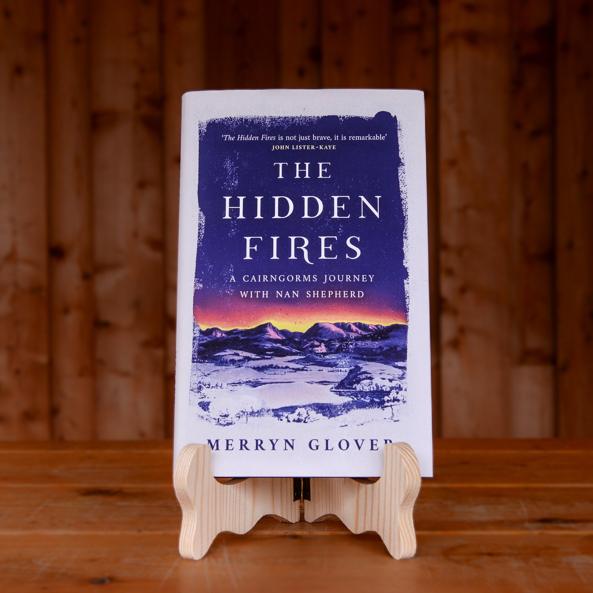 The book The Hidden Fires by Merryn Glover displayed on a book stand on a wooden table