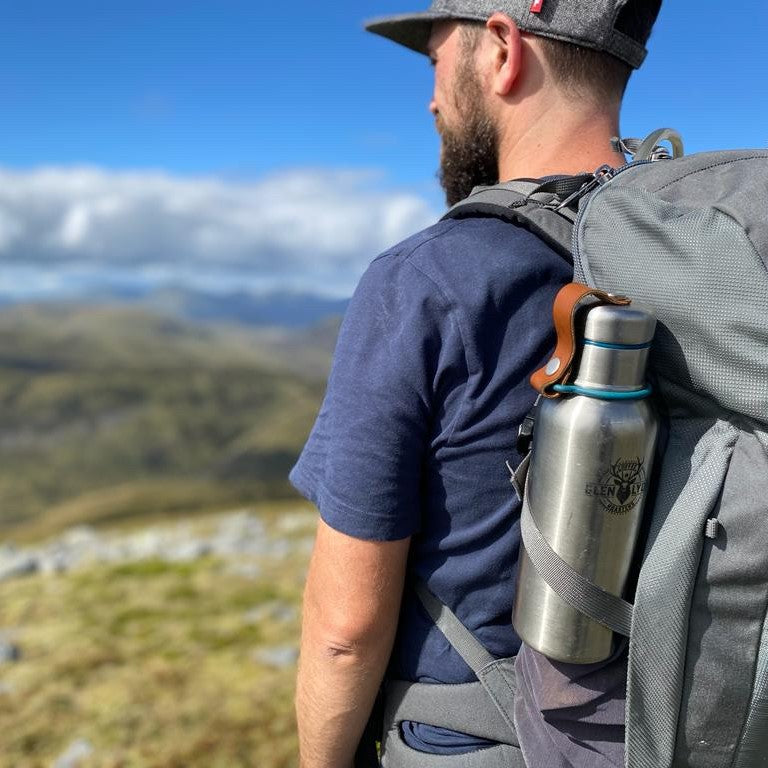 Medium shot of a person hillwalking, focused on a Glen Lyon Coffee bottle in their backpack
