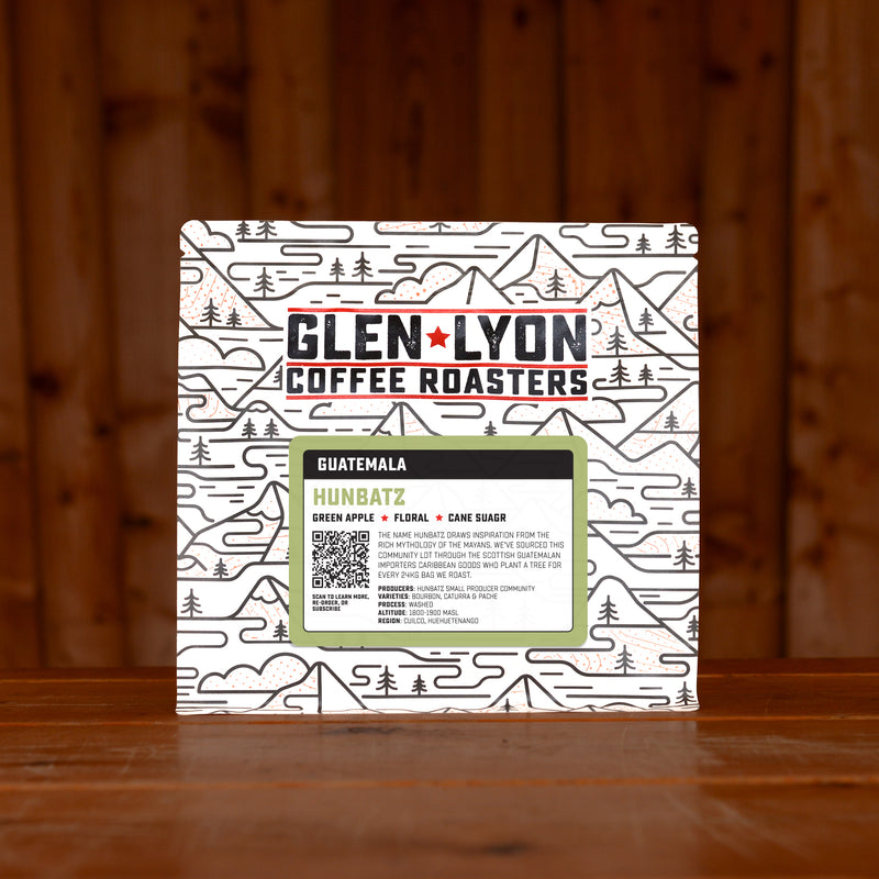 A 250g bag of Hunbatz from Glen Lyon Coffee Roasters coffee sits on a wooden table with a slatted wood background.