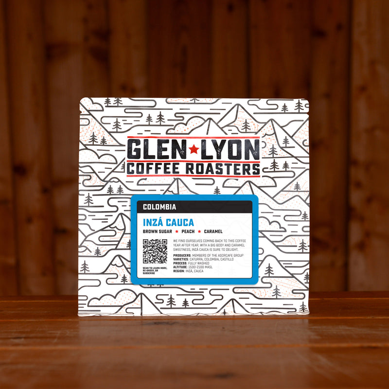 A 250g bag of Inza Cauca from Glen Lyon Coffee Roasters coffee sits on a wooden table with a slatted wood background.