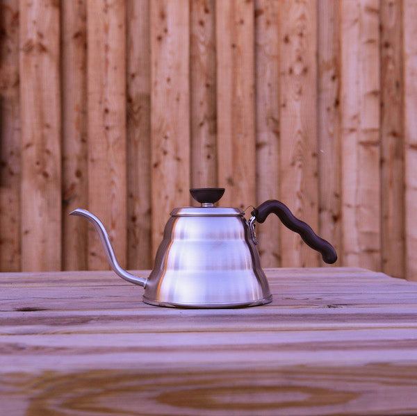 A Hario goose neck pouring kettle on a wooden table outside the Glen Lyon Coffee Roasters roastery cafe