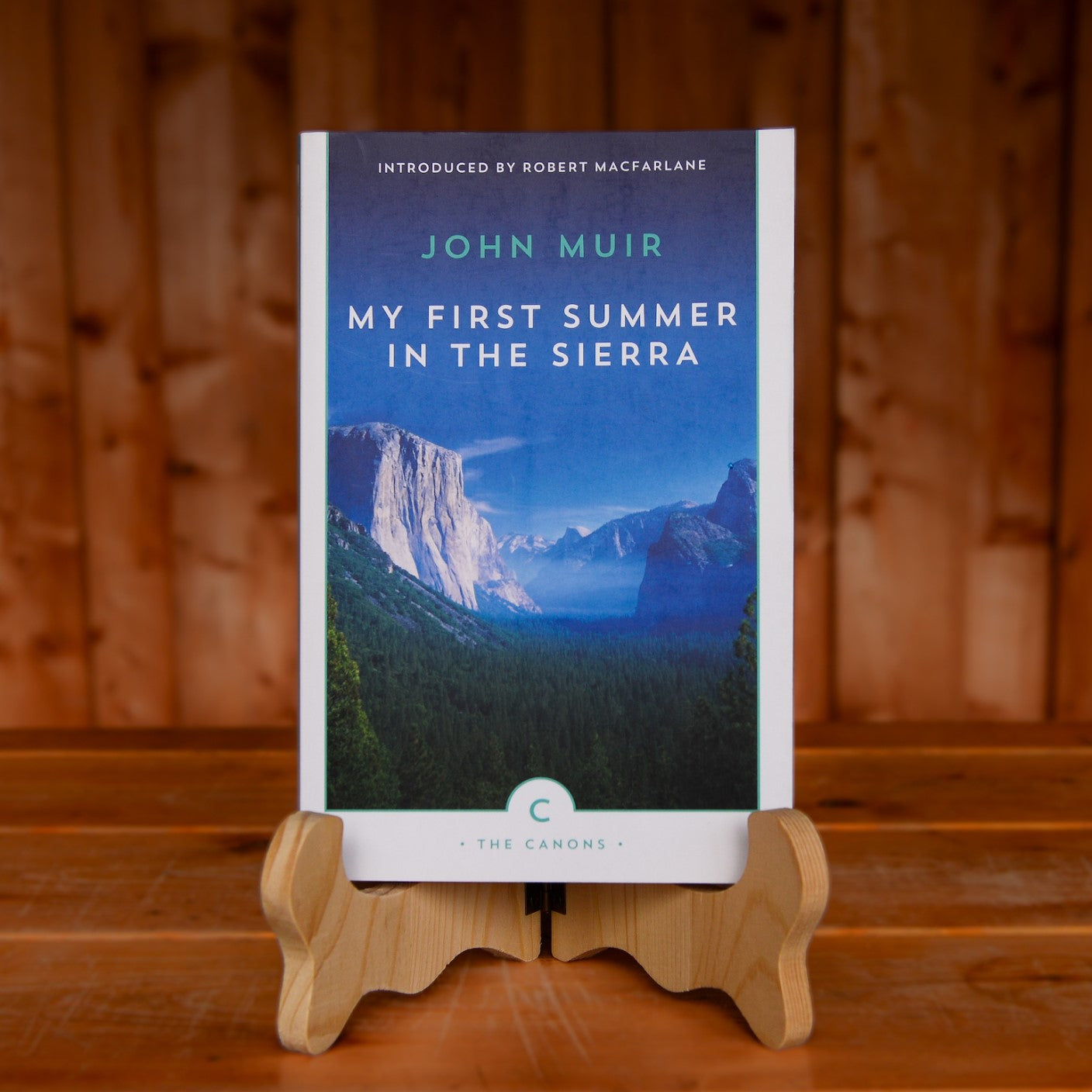 The book My First Summer in the Sierras by John Muir displayed on a book stand on a wooden table