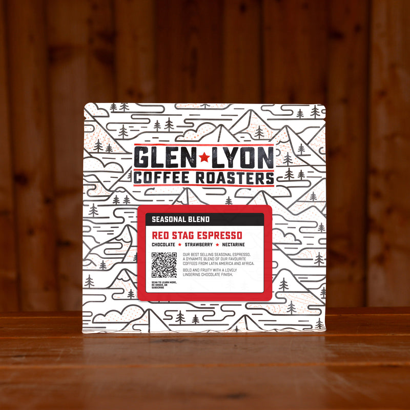 A 250g bag of Red Stag Espresso from Glen Lyon Coffee Roasters coffee sits on a wooden table with a slatted wood background.