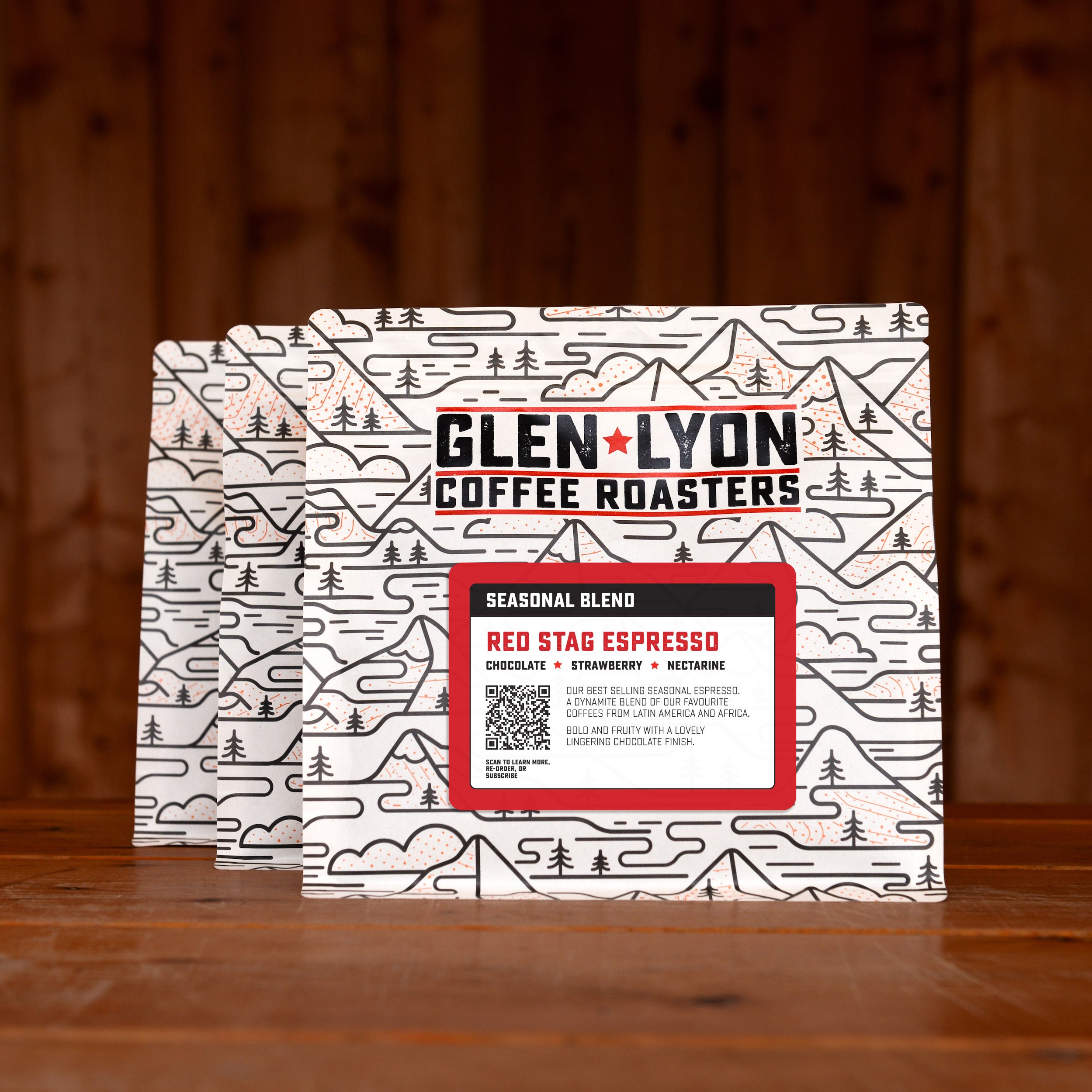 3 bags of Red Stag Espresso subscription labelled speciality coffee from Glen Lyon Coffee Roasters against a warm wood-tinged background