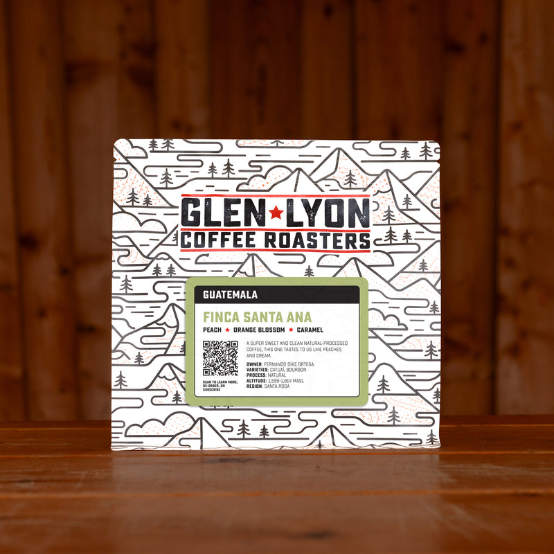 A 250g bag of Santa Ana from Glen Lyon Coffee Roasters coffee sits on a wooden table with a slatted wood background.