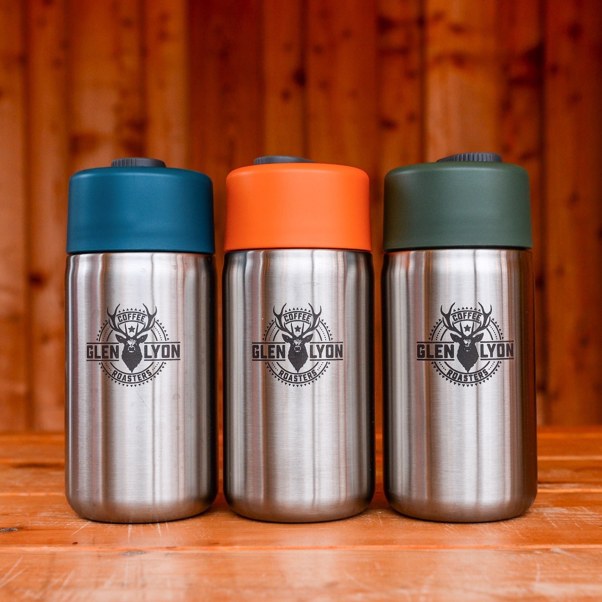 Three Glen Lyon Coffee Roasters branded stainless steel travel mugs with different coloured caps