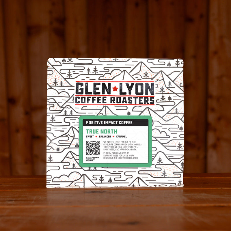 A 250g bag of True North from Glen Lyon Coffee Roasters coffee sits on a wooden table with a slatted wood background.