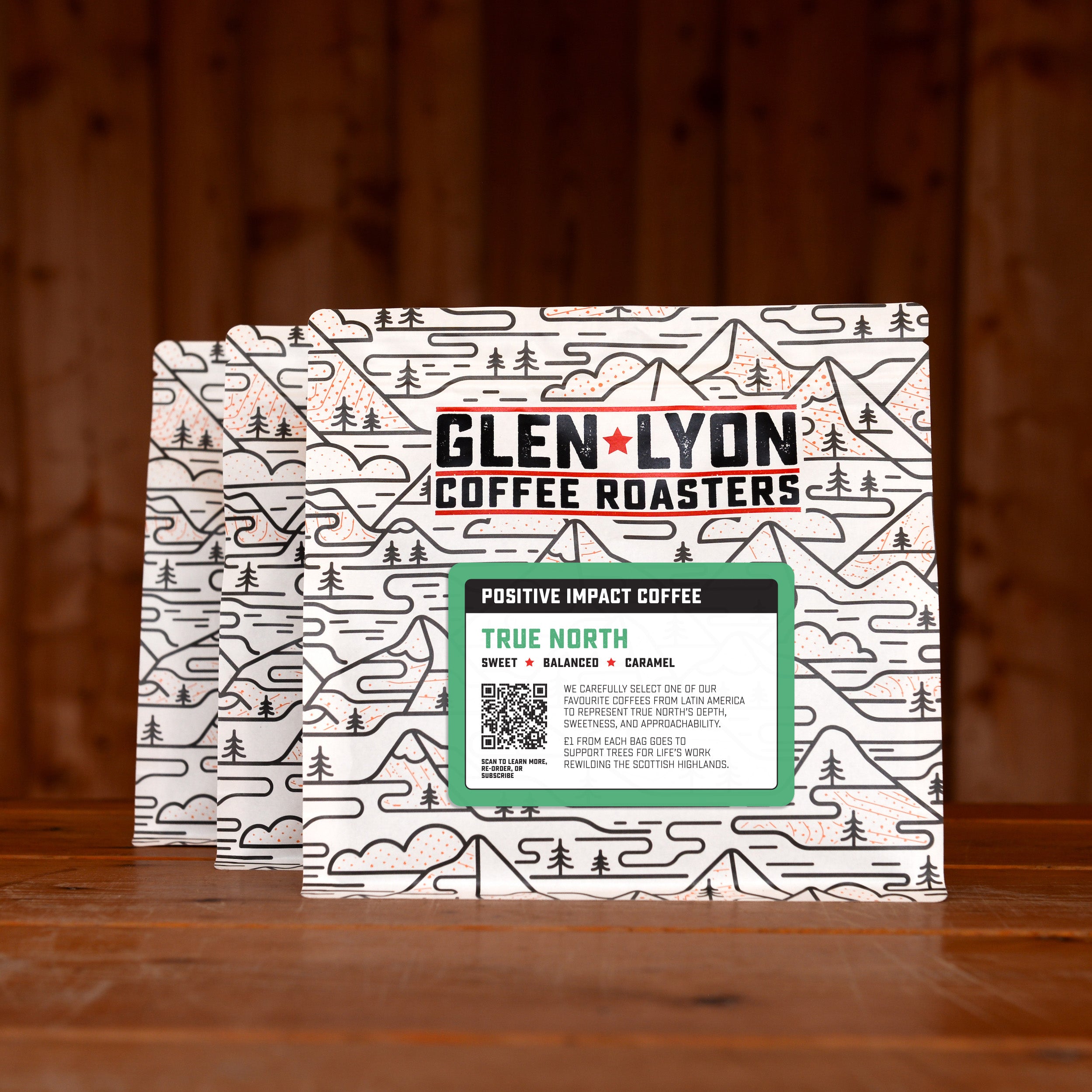 3 bags of True North subscription labelled speciality coffee from Glen Lyon Coffee Roasters against a warm wood-tinged background