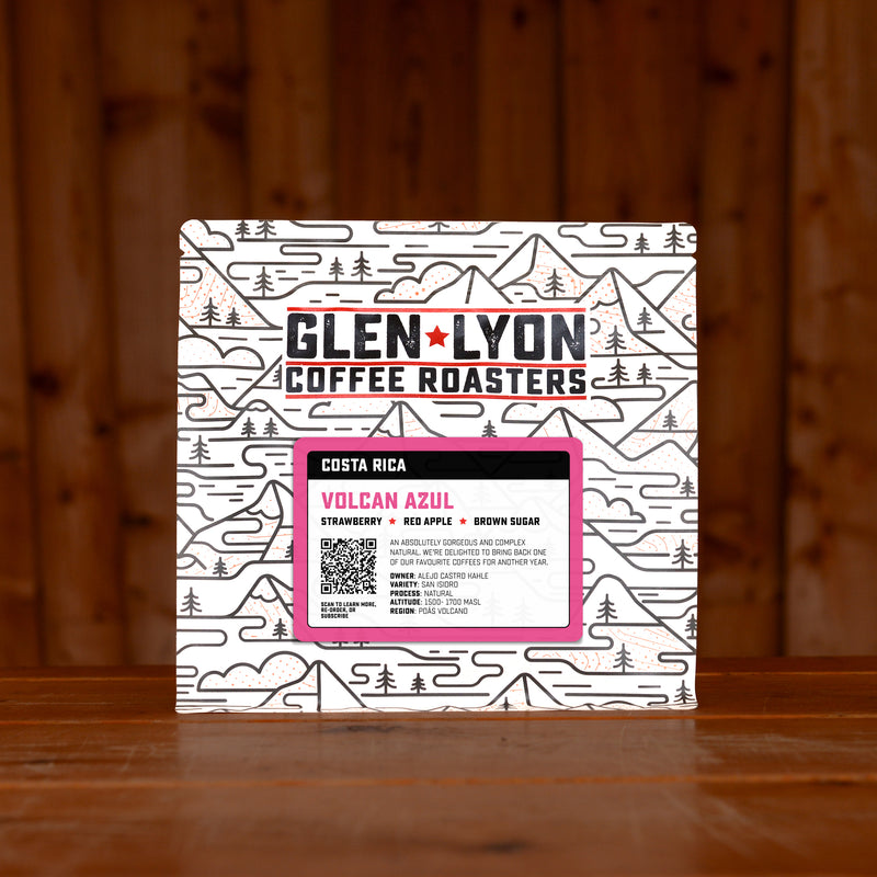 A 250g bag of Volcan Azul from Glen Lyon Coffee Roasters coffee sits on a wooden table with a slatted wood background.