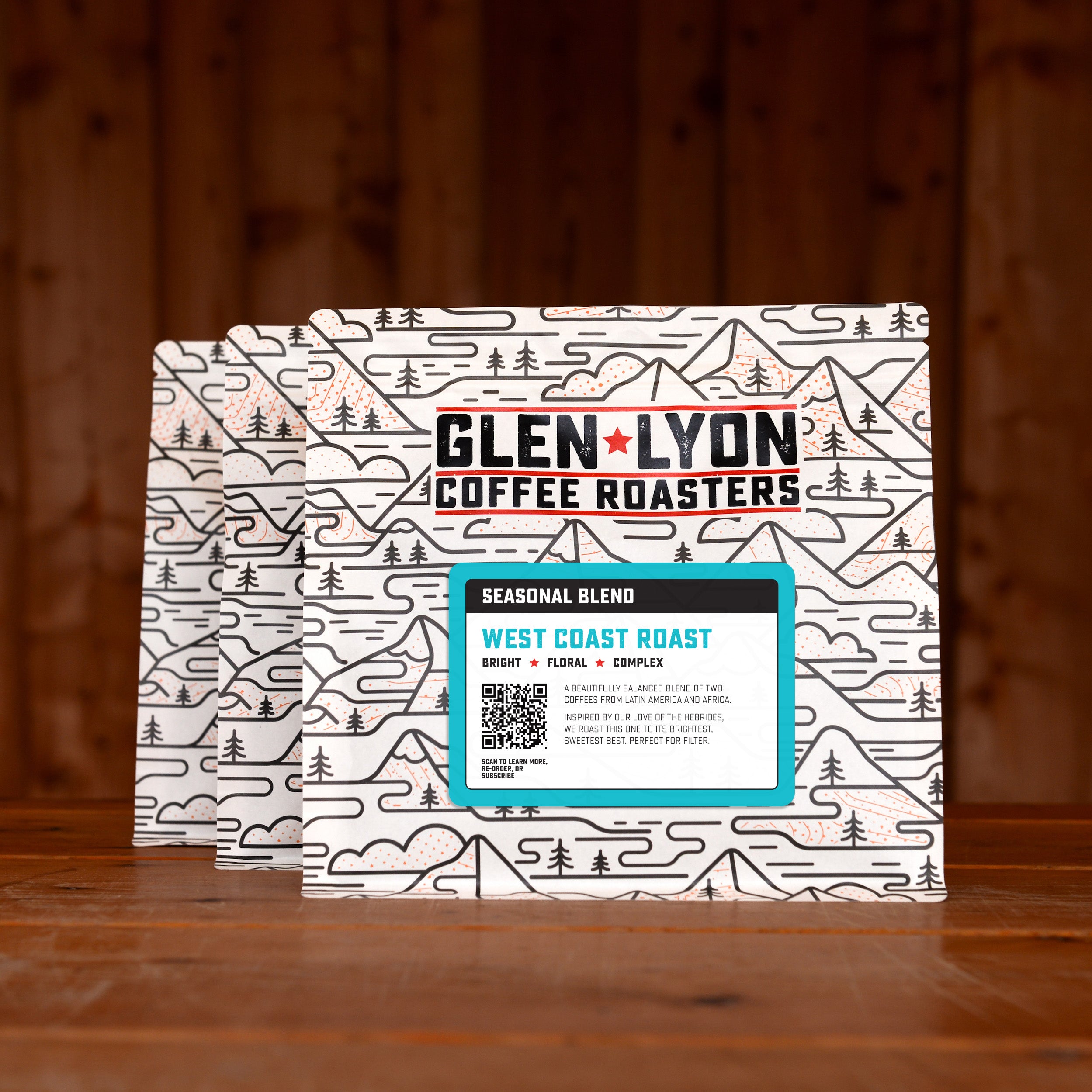 3 bags of West Coast Roast subscription labelled speciality coffee from Glen Lyon Coffee Roasters against a warm wood-tinged background