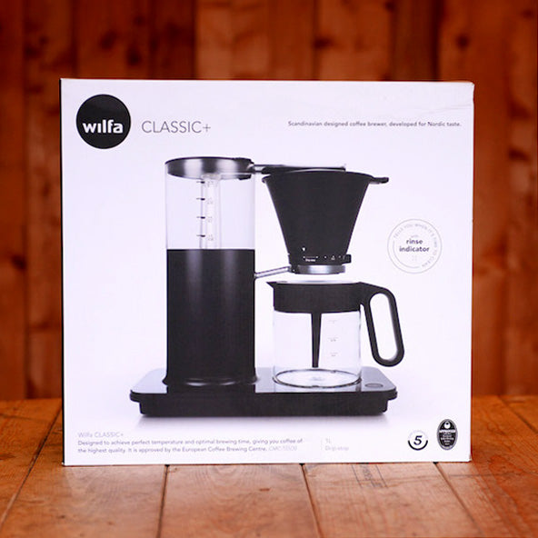 A Wilfa Classic+ filter coffee brewer in a white box on a wooden table