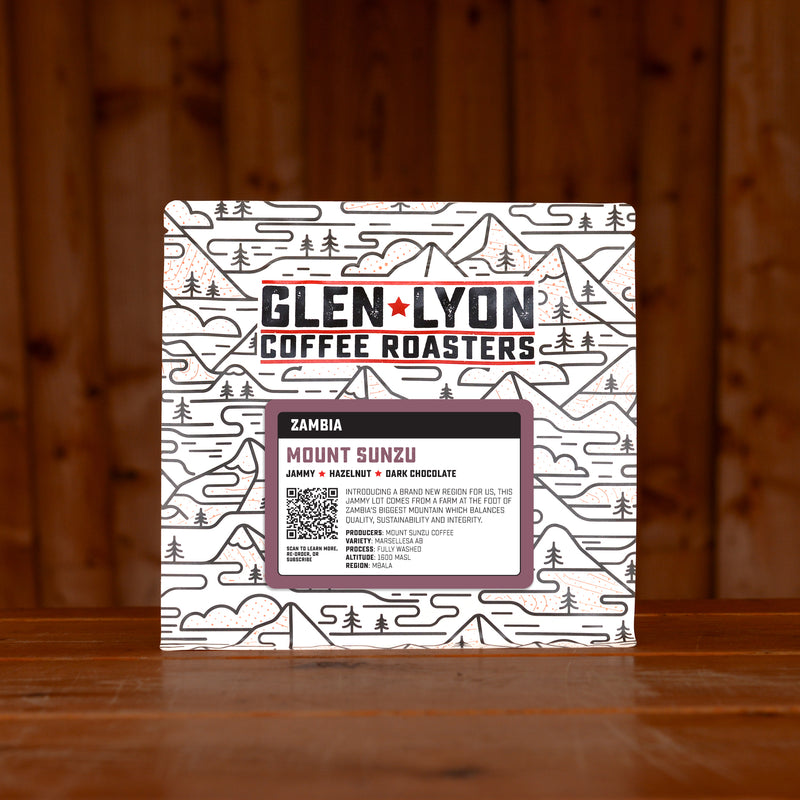 A 250g bag of Zambia Mount Sunzu from Glen Lyon Coffee Roasters coffee sits on a wooden table with a slatted wood background.