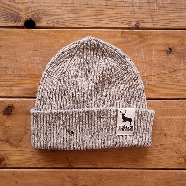 A speckled light grey, or "oat", Scottish wool beanie with a sewn-in tag with the Glen Lyon Coffee Roasters logo.