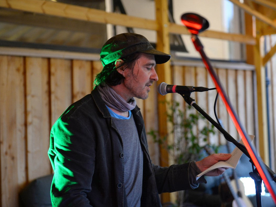 Mobile-size medium shot of a person standing in front of a microphone outside the Glen Lyon Coffee roastery cafe