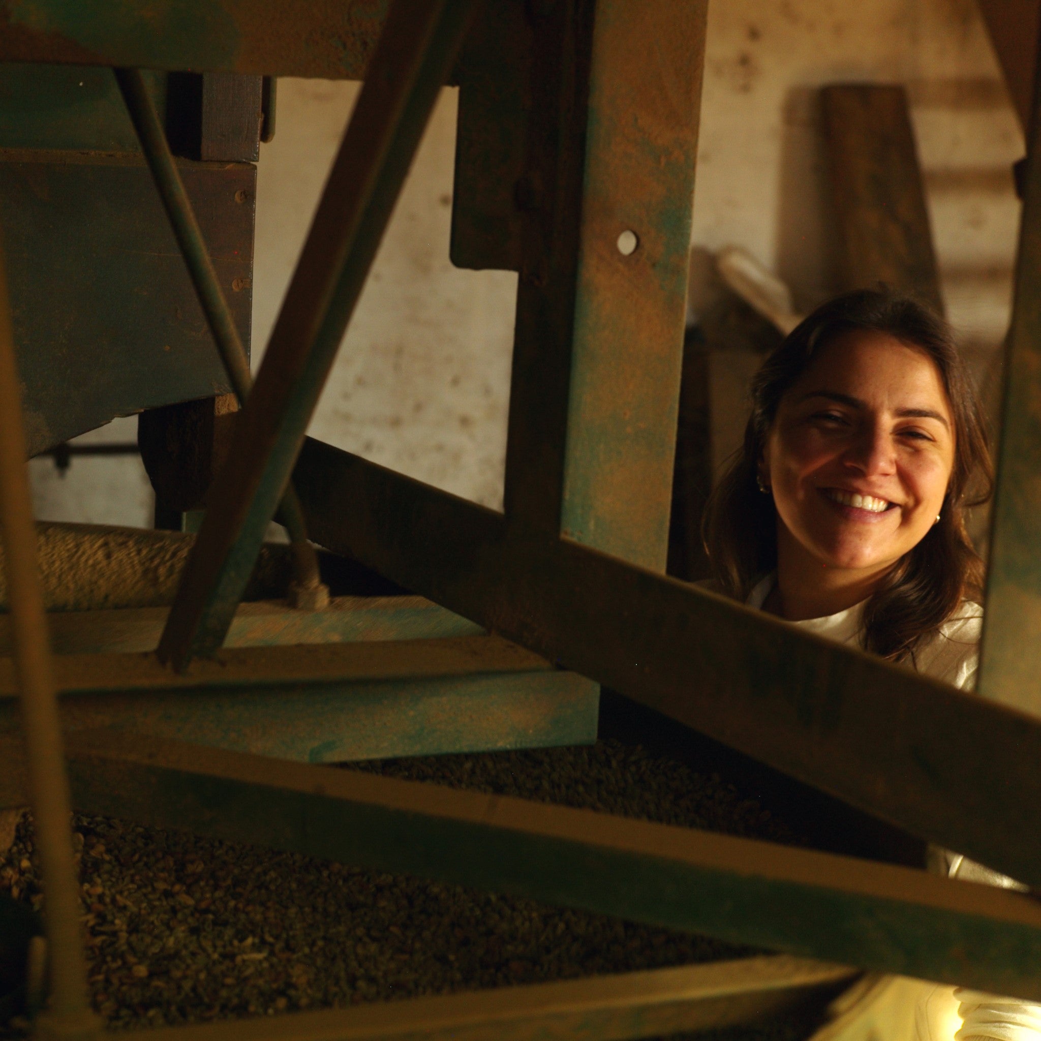 A green coffee fermentation tank with a smiling worker looking on