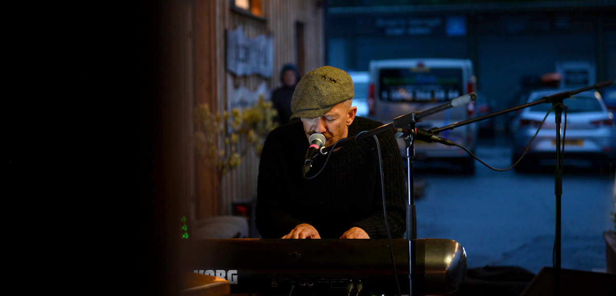 A musician playing the piano and singing outside the Glen Lyon Coffee roastery cafe