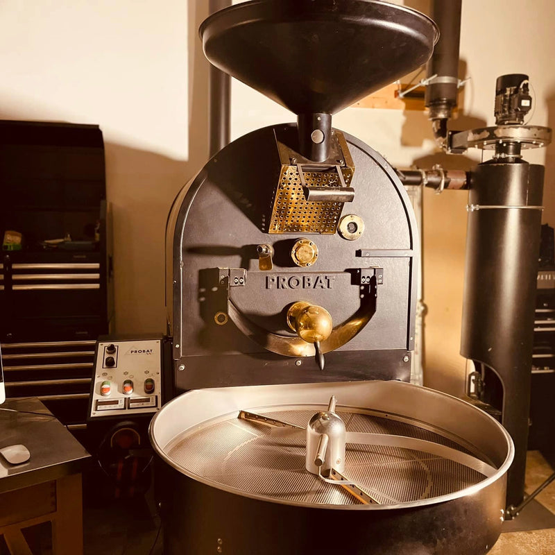 The 12.5kg Probat roaster, made of black steel and shiny gold accents, sits in the roastery at Glen Lyon Coffee Roasters.
