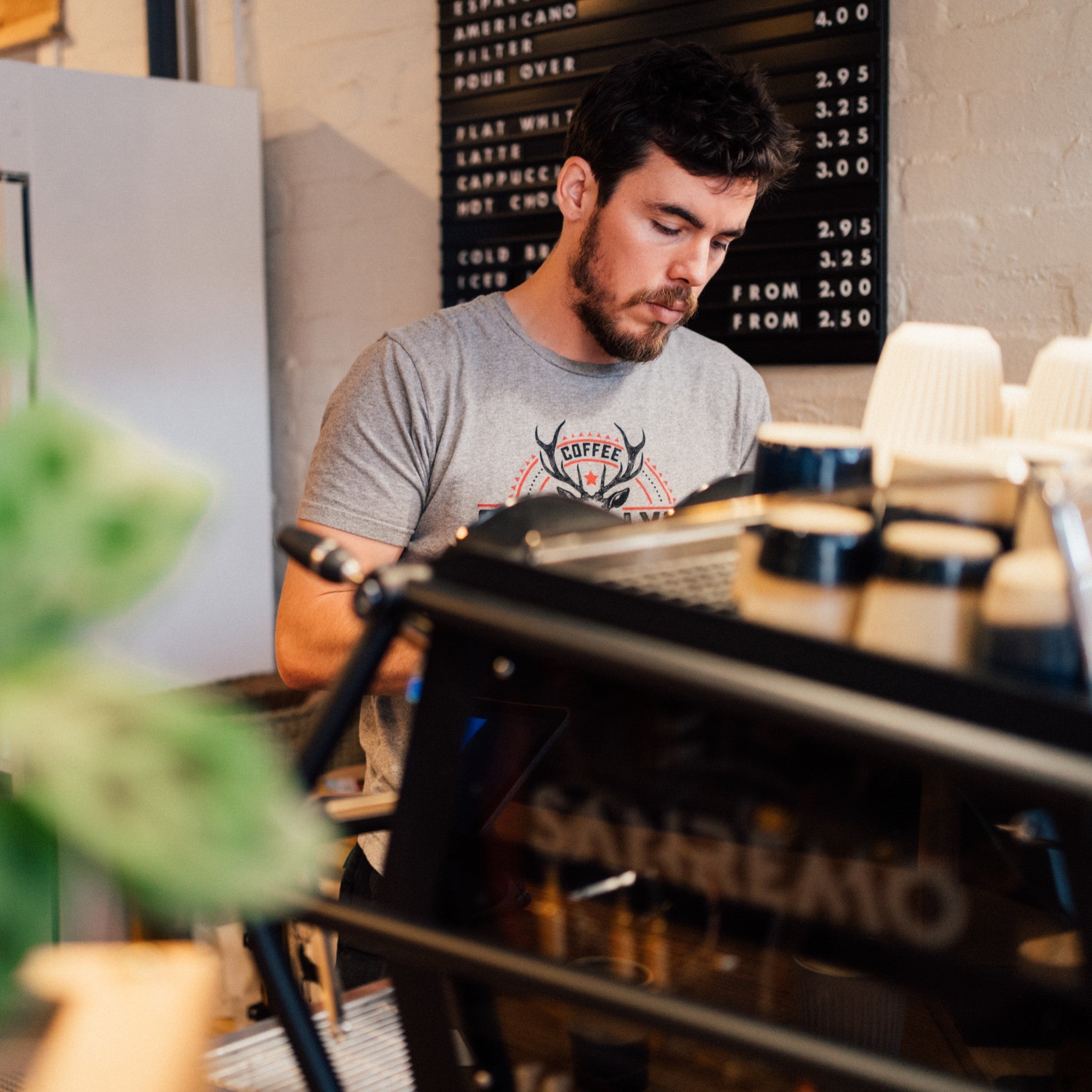 A speciality coffee barista works behind an espresso machine at the Glen Lyon Coffee roastery cafe
